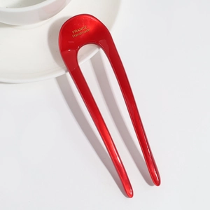 Close-up of a red U-shaped acetate hair pin with gold France Handmade lettering