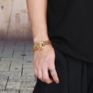 Gros plan d'un bracelet tête de lion doré pour homme avec chaîne gourmette double au poignet