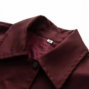 Detail of wine red coat fabric texture with matte black button and XS size tag