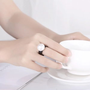 Elegant baroque black ring with a large white pearl shown on a minimalist background