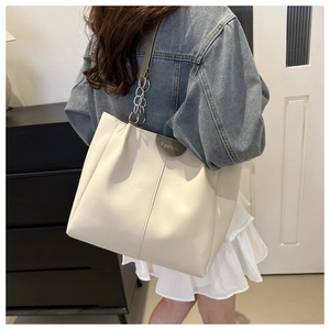 Moderna borsa tote in pelle bianco crema con tracolla a catena indossata da una modella