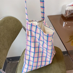 Detailed shot of a pastel plaid cotton tote bag with a zipper closure on a green chair