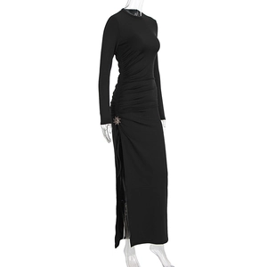 Détail d'une robe moulante noire à manches longues avec emblème soleil et fente latérale