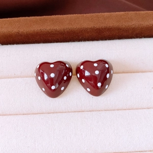 Detailed macro view of heart-shaped earrings with red oil drip finish and white polka dots