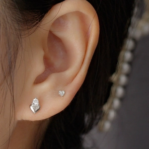 Close-up of 925 silver heart stud earrings with cubic zirconia on a female ear