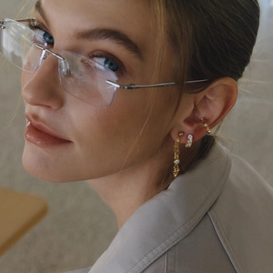 Close-up of gold 18K tassel earrings with white zircon on model wearing glasses