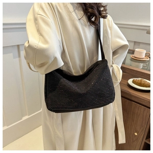 Détail d'un sac hobo noir orné de strass avec une bandoulière large et élégante