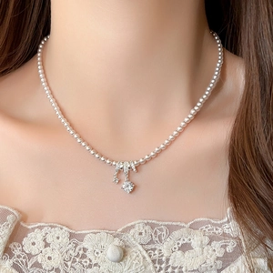 Close-up of pearl necklace with silver triple ring diamond pendant on a model neck