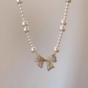 Detail of elegant pearl necklace featuring a gold bow pendant encrusted with cubic zirconia
