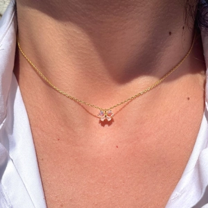 Elegant gold-plated butterfly pendant necklace with cat-eye stone worn by a female model
