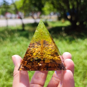 Detailed close-up of a resin orgone pyramid with peridot tree and tiger eye stones