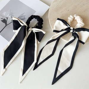 Close-up of elegant satin bow hair ties with contrasting edges on a minimalist tray