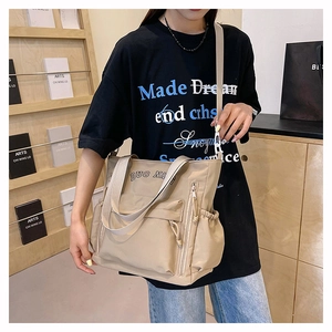 Detailed view of khaki nylon tote bag with large capacity and side pockets on a model
