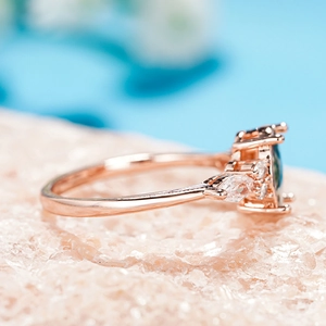 Detail of rose gold ring with marquise teal gemstone and white accent stones
