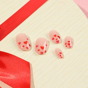 Glossy nude press-on nails with red heart patterns on a heart-shaped wooden gift box
