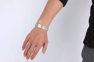 Polished silver stainless steel watch-style link bracelet worn on a wrist