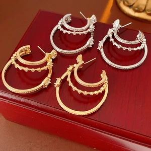 Detail of gold and silver multi-layered hoop earrings with inlaid rhinestones on a wooden box