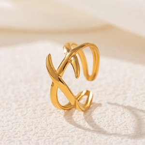 Detail shot of a gold-plated stainless steel criss-cross ring on white fabric