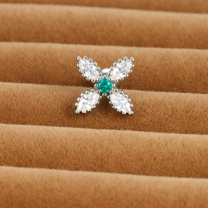Macro shot of silver floral cartilage stud with green zircon and white crystals
