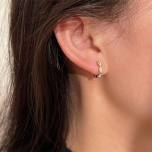 Close-up of gold S925 sterling silver huggie earrings with three marquise-cut zircons