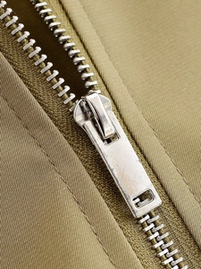 Vue macro détaillée de la fermeture éclair en métal argenté sur une veste d'hiver kaki olive