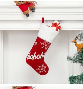 Detail of red plush Christmas stocking with white hohoho embroidery on a white mantel