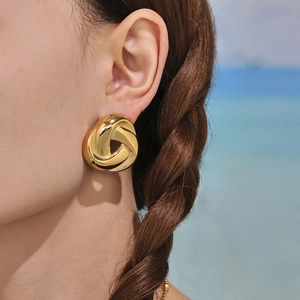 Polished 18K gold triangle geometric knot stud earrings worn by model on beach