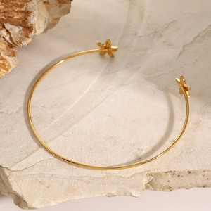 Macro detail of gold-plated starfish bangle on natural stone background