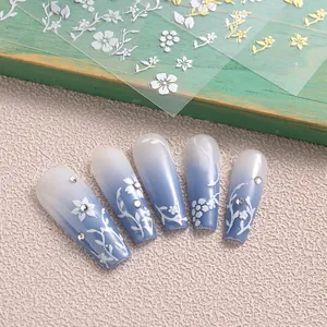 Detail of floral nail stickers featuring white cherry blossoms and golden leaf accents