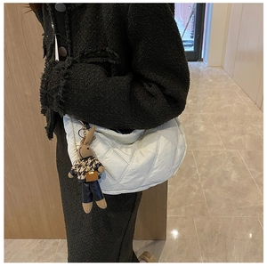 Close-up of a white quilted crossbody bag featuring a cute plush bunny charm on the strap