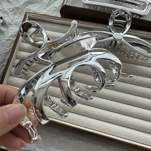 Macro view of octopus-shaped silver hair claw clip with smooth metallic finish and shine
