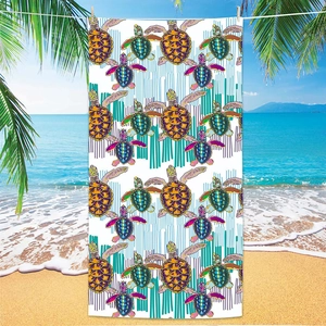 Vibrant sea turtle print microfiber beach towel hanging on a tropical sandy beach scene