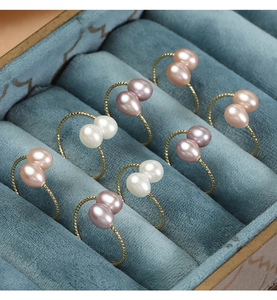 Detailed macro of gold twisted band rings with double freshwater pearls in blue velvet box