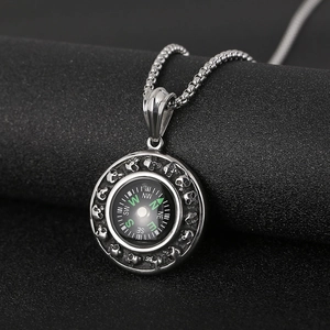 Macro view of vintage silver compass pendant with skull carving details on black background
