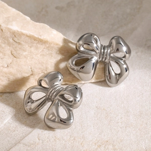 Macro shot of polished silver bow-shaped earrings with a metallic mirror finish