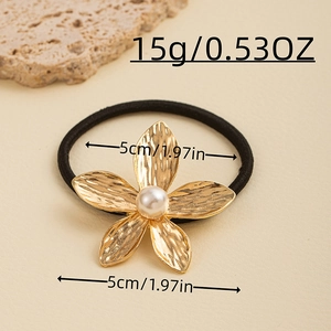 Macro view of golden metal flower hair tie with white pearl center and hammered texture