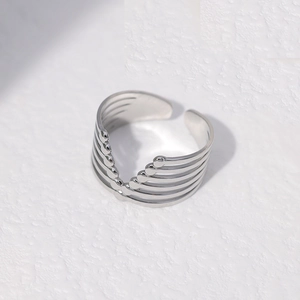 Detailed close-up of multilayer overlapping stainless steel open ring on white stone surface