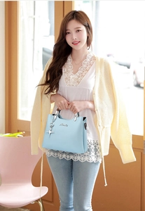Detail of light blue textured leather handbag with silver star charm and metal hardware