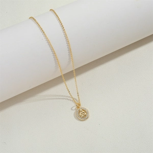 Macro detail of a 14K gold plated necklace featuring an oval snake pendant with white crystals