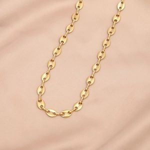 Macro shot of gold coffee bean link chain on satin fabric, showing metallic details