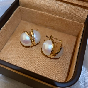 Close-up of elegant gold U-shaped pearl earrings on a soft brown velvet jewelry box