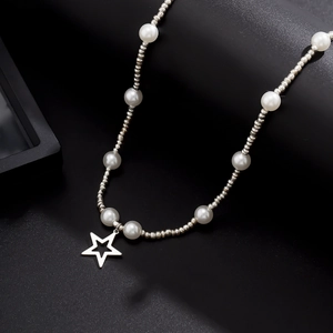 Hip hop pearl necklace with star pendant and silver beads on a textured surface