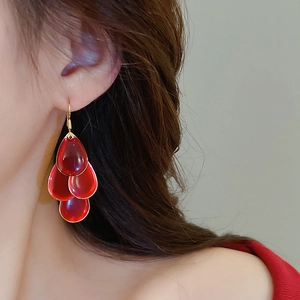 Detail of red teardrop tassel earrings with four layered resin pieces and gold hooks