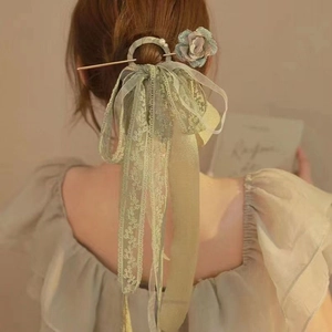 Detailed shot of sage green silk rose hair clip with lace ribbons and pearls on a model