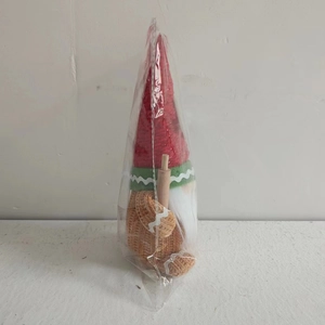 Detail of Christmas gingerbread gnome doll with red hat and wooden rolling pin
