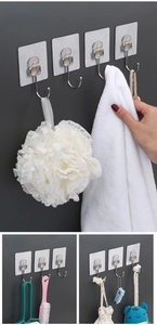 Detailed views of transparent adhesive wall hooks holding towels, brushes and bags