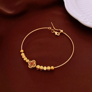 Detail of 18k gold beaded bracelet with red gemstone clover charm on dark leather