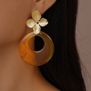 Detailed side view of resin earrings with golden flower accents and amber round rings