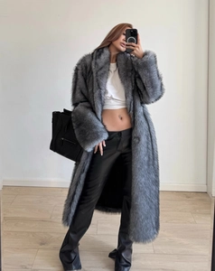 Detail view of long grey faux fur coat paired with black leather trousers and handbag