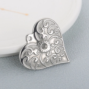 Polished heart shaped stainless steel pendant for jewelry making on a white plate